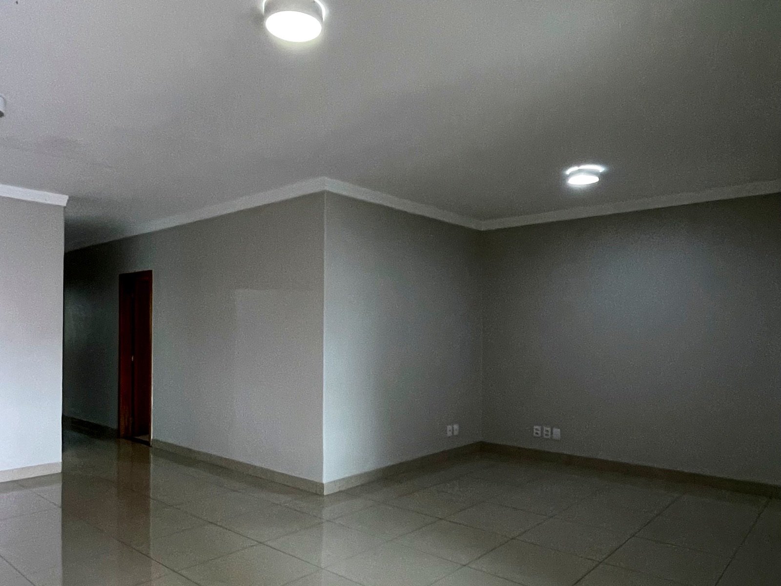 A mesma sala vazia, com piso de porcelanato e coluna de canto
